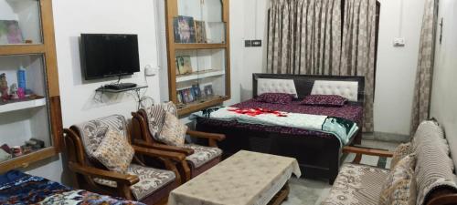 Cette chambre comprend un lit, des chaises et une télévision. dans l'établissement Harman paying guest house, à Ayodhya