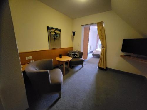 Hotel Sonne في زايفن: غرفة معيشة مع طاولة وكراسي وتلفزيون