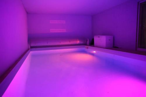 an empty room with pink lights in a room at Villa avec piscine intérieure in Holtzheim