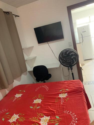 a bedroom with a red bed and a television on the wall at Quarto e sala para carnaval in Salvador