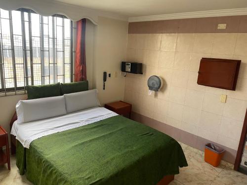 a bedroom with a bed with a green blanket at Hotel Brisas Real in Bogotá