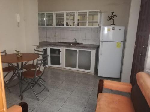 a kitchen with a white refrigerator and a table at Rento Suite amoblada al norte de Machala in Machala