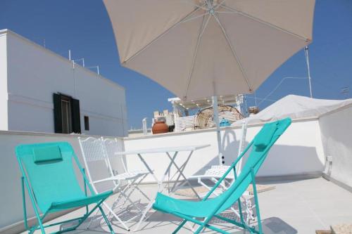 2 Stühle und ein Tisch und ein Sonnenschirm auf dem Balkon in der Unterkunft Palazzo Scianni in Monopoli