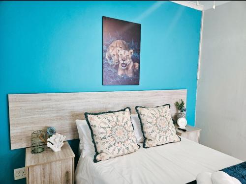 1 dormitorio con 1 cama con pared azul en Sea Breeze Manor - Aqua Unit, en East London