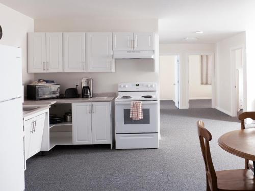 uma cozinha com armários brancos, um fogão e uma mesa em Prospectors Inn em Kirkland Lake