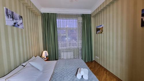 a bedroom with a bed and a window with green curtains at Mayden Family Apartment in Baku