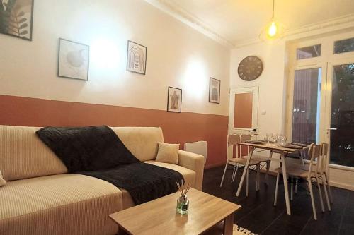 uma sala de estar com um sofá e uma mesa em Appartement cosy jardin en ville em Angoulême