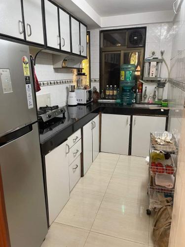 a kitchen with white cabinets and a refrigerator at Bandra west 2bhk in Mumbai