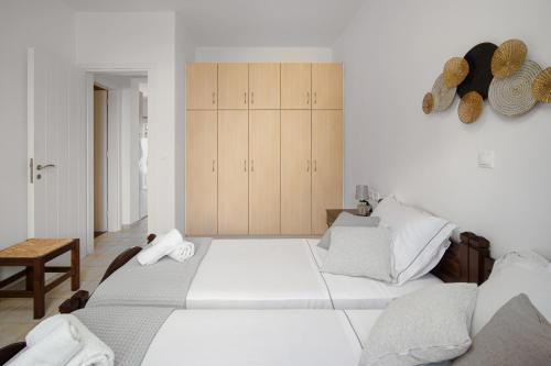 a white bedroom with two beds and a chair at Palos Studios in Livadion