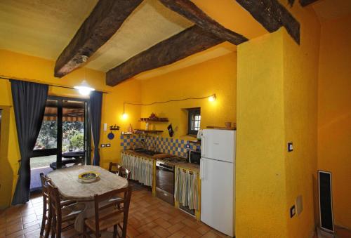 a kitchen with yellow walls and a table and a white refrigerator at Villa Relax a 2 Piani e Giardino Privato con Vista sulle Colline Umbre in Piloni