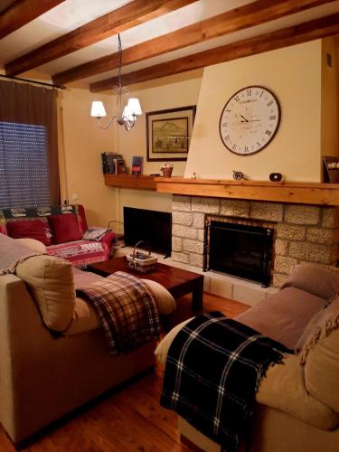 a living room with a fireplace and a clock on the wall at Casa Cotis Beceite in Beceite