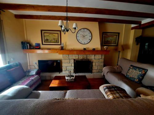 a living room with couches and a fireplace with a clock at Casa Cotis Beceite in Beceite