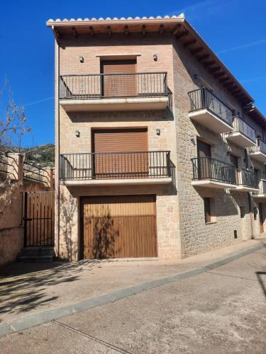 a brick building with two garage doors and two balconies at Casa Cotis Beceite in Beceite