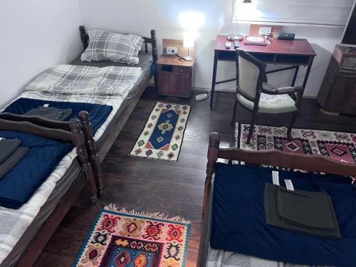 a room with two beds and a desk and a table with rugs at Prenoćište Jocic in Pirot