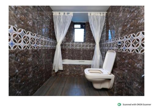 a bathroom with a toilet and a window at Exotica Villa in Lonavala