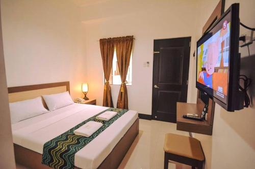 a bedroom with a bed and a flat screen tv at DRIGGS SUITES in General Santos