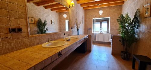 uma grande casa de banho com 2 lavatórios e um espelho grande em El Almendro del Cura em Villarmayor