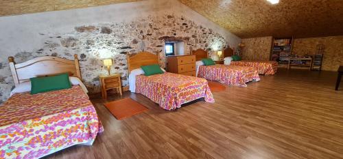 1 dormitorio con 3 camas y pared de piedra en El Almendro del Cura en Villarmayor