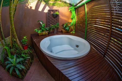 a bath tub on a wooden deck with potted plants at Hotel Canto do Rio Maresias in Maresias