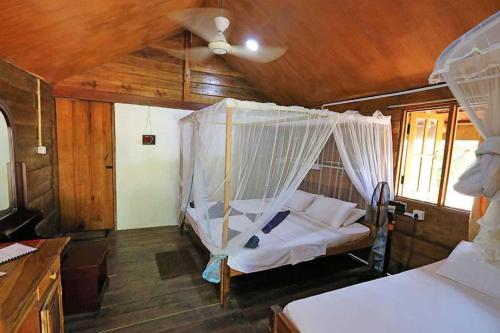 Schlafzimmer mit einem Bett mit Moskitonetz in der Unterkunft Golden Beach Chalets in Arugam Bay