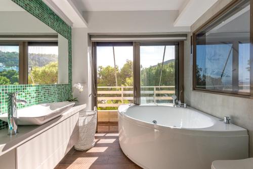 a bathroom with two sinks and a tub and windows at Cozy Riviera Apartment in Varkiza