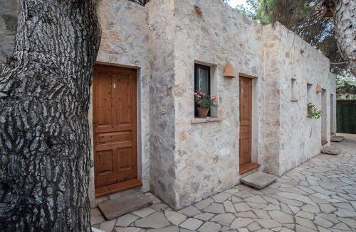 un edificio de piedra con una puerta de madera junto a un árbol en La Pérgola Habitaciones Rústicas en Es Pujols