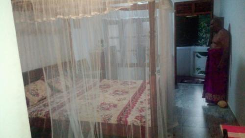 1 dormitorio con 1 cama con cortina en Jayanika home stay, en Tangalle