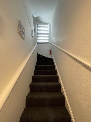 a stairway with a staircase leading up to a window at Luna - Deluxe London Studio Flat in South Norwood