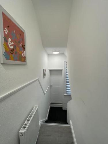 un pasillo con una escalera con una escalera blanca en Luna - Deluxe London Studio Flat en South Norwood