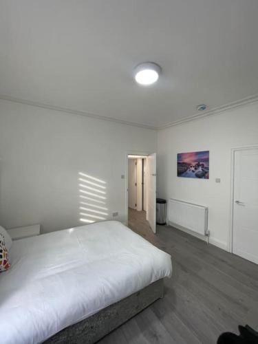Un dormitorio blanco con una gran cama blanca. en Luna - Deluxe London Studio Flat en South Norwood