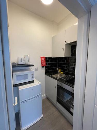 a small kitchen with a stove and a sink at Luna - Deluxe London Studio Flat in South Norwood