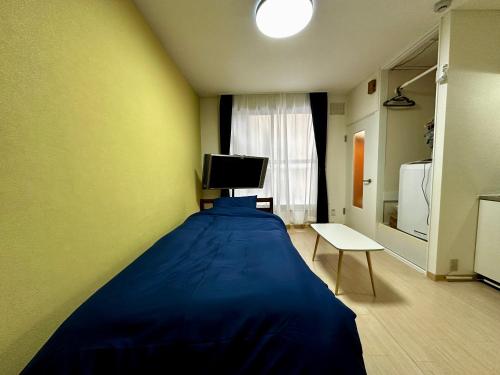 1 dormitorio con 1 cama azul en una habitación en 1-3サン　地下鉄徒歩圏内サービスアパ―トメントSAPPORO Shiroish iStation エアコンネット完備 en Tsukisappu