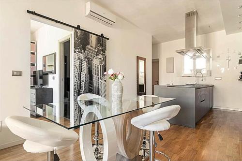 comedor con mesa de cristal y sillas blancas en City Life Milan Apartment - Wi-Fi & Smart TV, en Milán