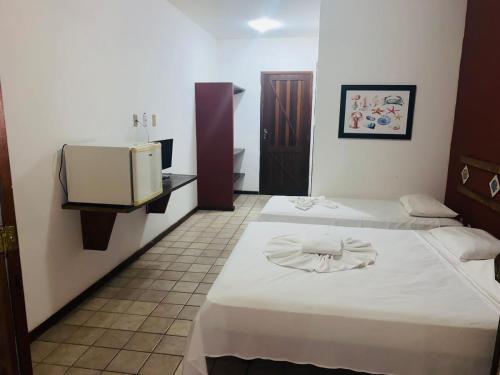um quarto de hotel com duas camas e uma televisão em Pousada Thalud em Imbassaí