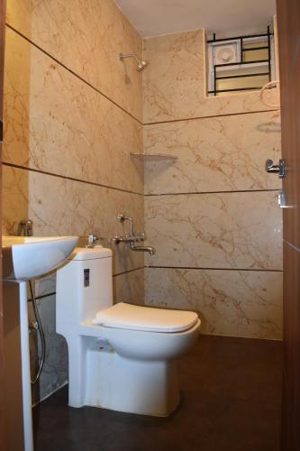 a bathroom with a white toilet and a sink at Stellar homes Ooty in Ooty