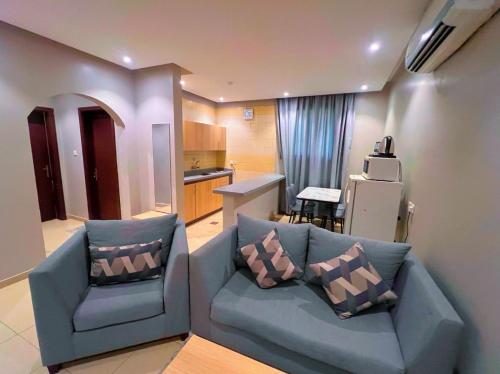 sala de estar con sofá azul y cocina en السعادة سويت - الملز الرياض Saada Suites Serviced Apartments en Riad