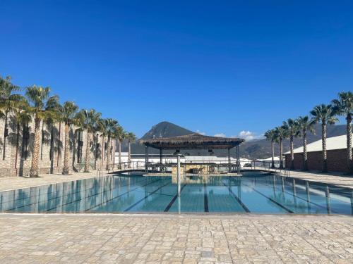 uma piscina com um gazebo e palmeiras em Rozafa Fish City Hotel em Labinot i Poshtëm