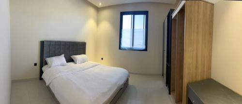 Al Azmy Al Ared Hotel في الرياض: غرفة نوم بسرير وملاءات بيضاء ونافذة