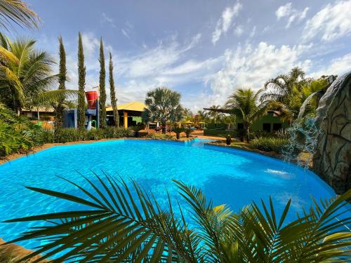 a large blue swimming pool with palm trees and houses at Hotel Dolce Dulce in Olímpia