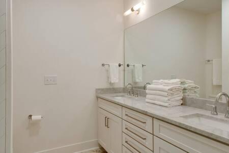 a bathroom with two sinks and a large mirror at The Dawson - Gulch Elegance, Green Rooftop Retreat in Nashville