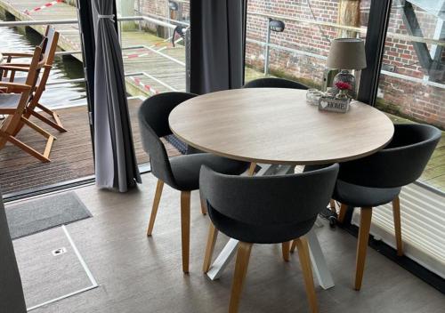 a table and chairs in a room with a window at Hausboot Lobster Bremerhaven in Bremerhaven