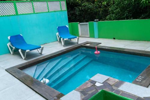 einen Pool mit zwei blauen Stühlen und einem Pool in der Unterkunft Bougainvillea Apartments 2 in Castries