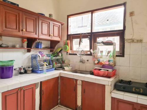 cocina con armarios de madera, fregadero y ventana en Homestay Pesona Sintuk Bontang A9, en Bontang
