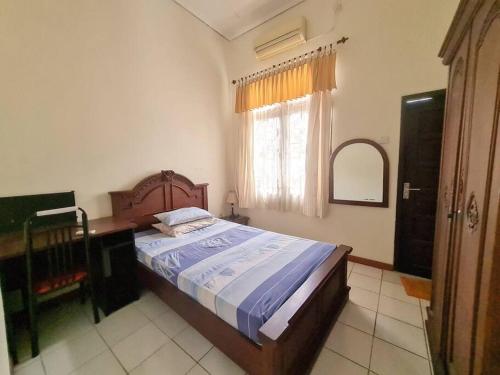 a bedroom with a bed and a desk and a window at Homestay Pesona Sintuk Bontang A9 in Bontang