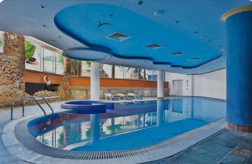 a large swimming pool with a blue ceiling at Paphos gardens studio suite in Paphos