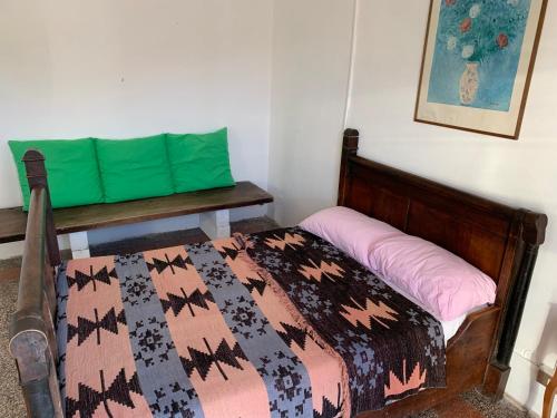 a bedroom with a bed with a green pillow and a bench at casa Berzano in Vallegioliti