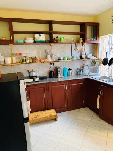 uma cozinha com armários de madeira e um frigorífico em Haika Hilltop Hideaway em Sokon