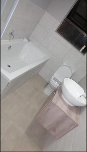 ein weißes Bad mit einem WC und einem Waschbecken in der Unterkunft Home away from Home in La Mercy in La Mercy