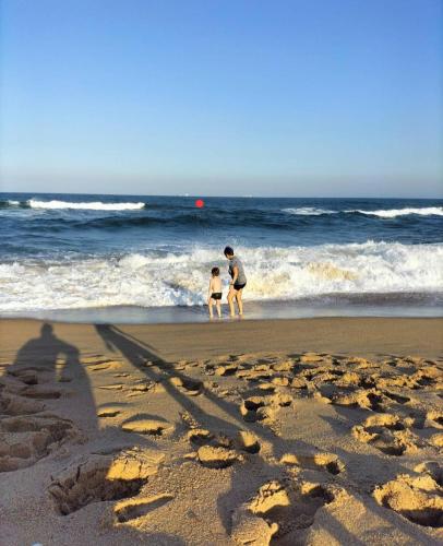 a man and a child standing on a beach at Home away from Home in La Mercy in La Mercy