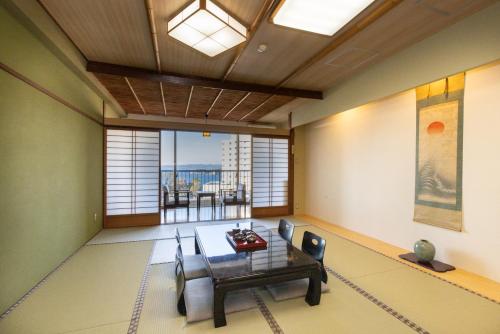 een woonkamer met een tafel en uitzicht op de oceaan bij Shirahama Onsen Kisyu Hanto in Shirahama